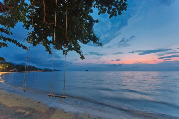 Balançoire en bois accrochée à un arbre sur une plage et coucher de soleil — Photo