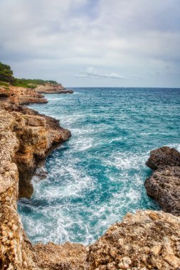 Kasvetli bir dramatik gökyüzü altında kayalık plaj