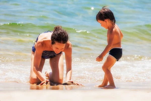 Mama Grać Małym Synem Plaży Świetle Słonecznym Rozmazanym Tle Morza — Zdjęcie stockowe