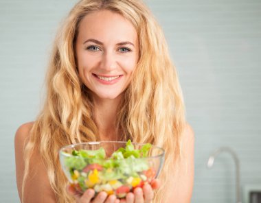 Genç bayan mutfakta sebze salatası hazırlıyor.