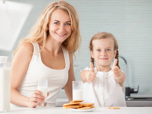 Child with mother drinking milk. Happy family eating at home