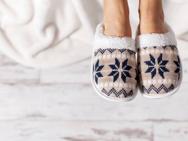 Terlik bir ahşap zemin çerçevede kadın bacaklar. Rahat, sıcak ve rahat terlik ayakları üzerinde