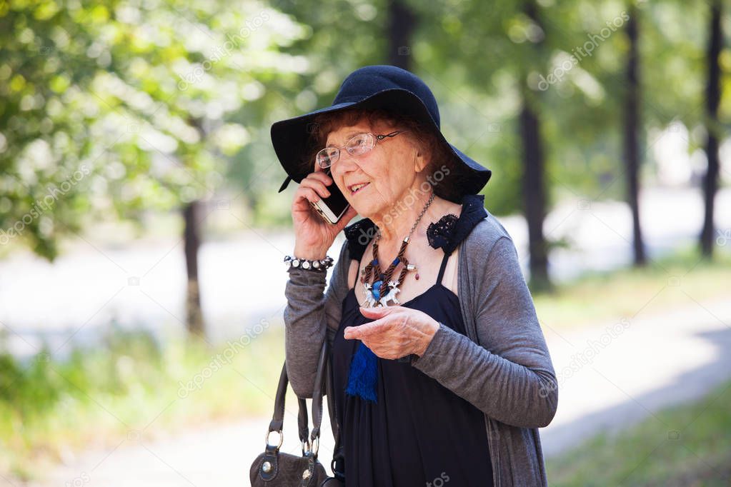 Stylish 90 years old woman walking around city and speaking phone. Granny female outdoors