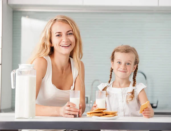 Child with mother drinking milk. Happy family eating at home
