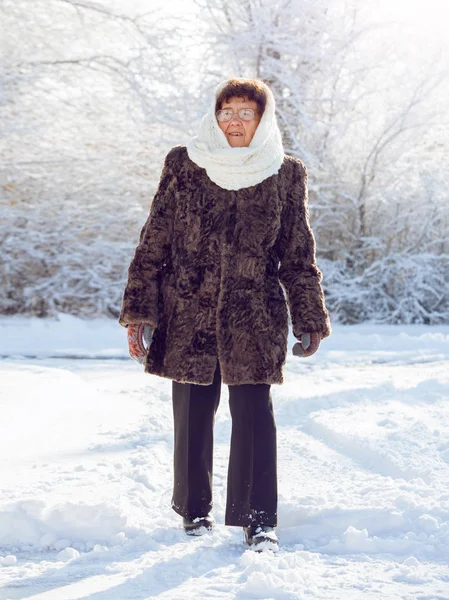 Old woman walking at winter park. Senior outdoors
