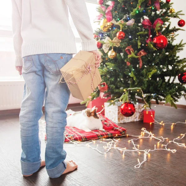 Niño cerca del árbol de Navidad con un regalo detrás —  Fotos de Stock