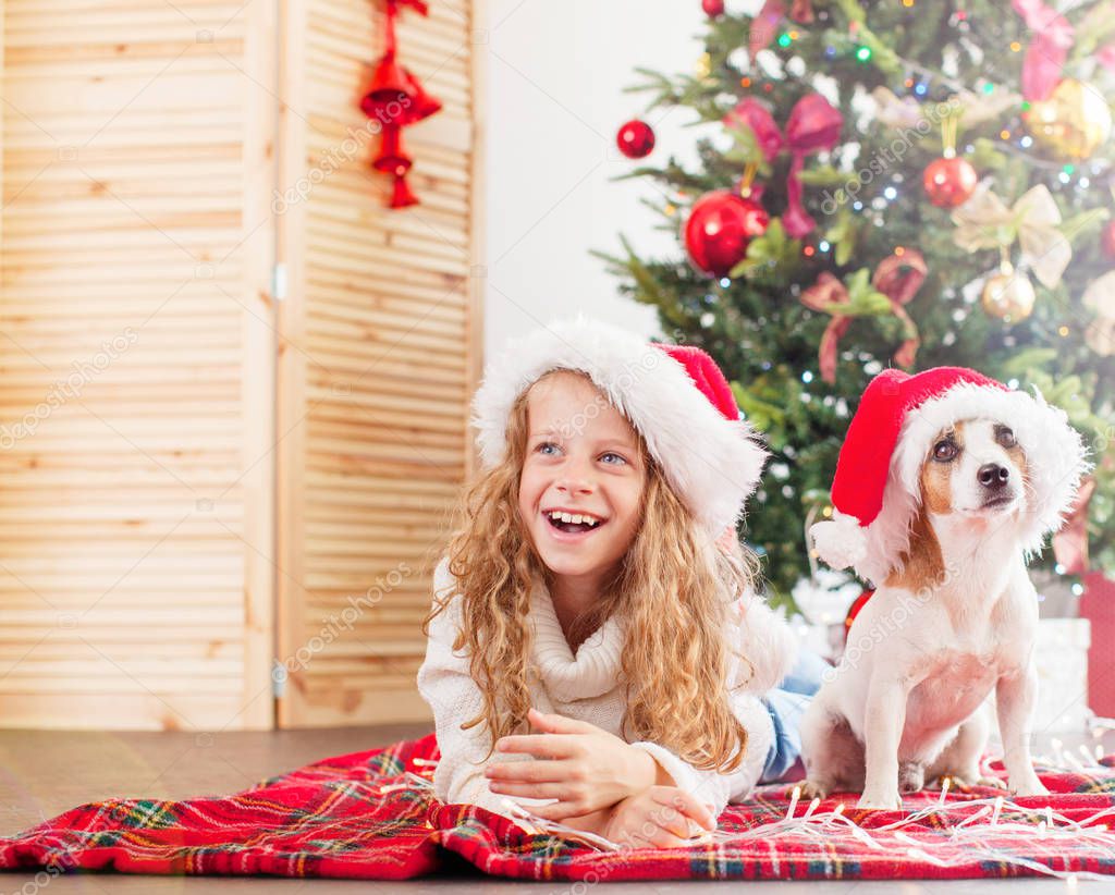 Child with dog near christmas tree