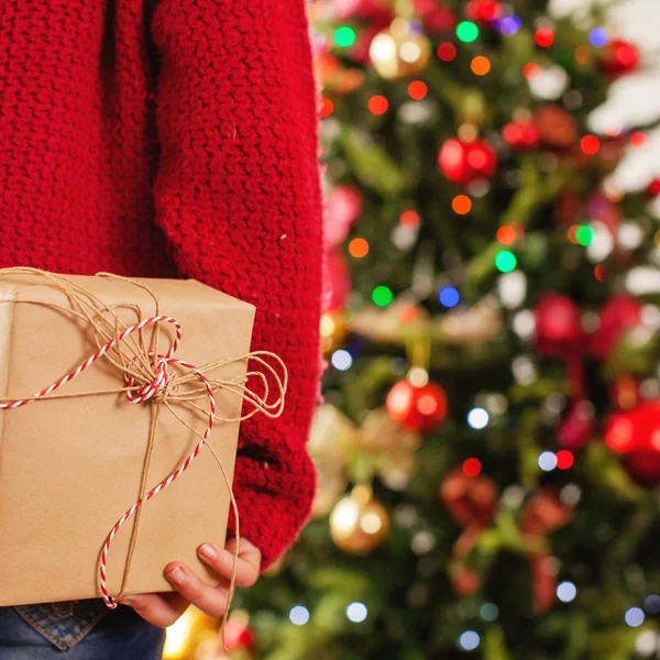 Child near the Christmas tree with a gift behind — Stock Photo, Image