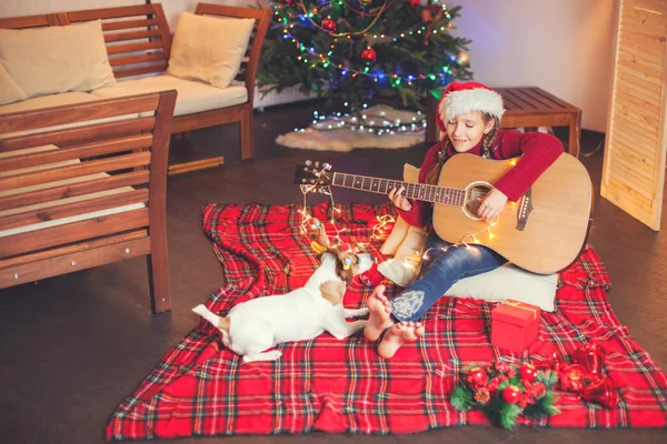 Mädchen mit Hund spielt Gitarre und singt kurz vor Weihnachten — Stockfoto