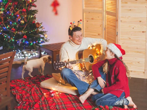 Mädchen mit Papa, der Gitarre spielt und kurz vor Weihnachten singt — Stockfoto