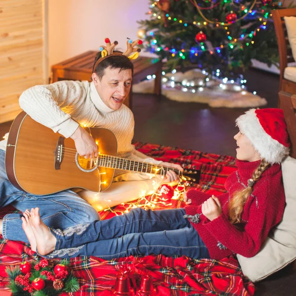 Mädchen mit Hund spielt Gitarre und singt kurz vor Weihnachten — Stockfoto