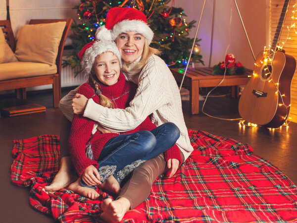 Smiling girl with mom near christmas tree at home