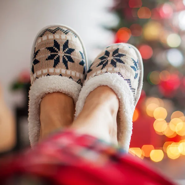 Legs in slippers on Christmas tree background — Stock Photo, Image