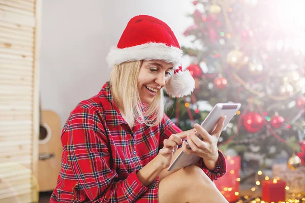 Mujer usando tableta delante del árbol de navidad —  Fotos de Stock