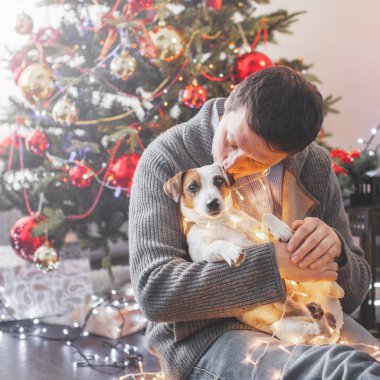 Noel ağacının yanında köpeği olan bir adam
