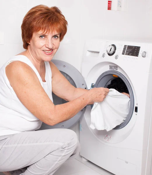 Kadın çamaşır makinesine çamaşır koyuyor. — Stok fotoğraf