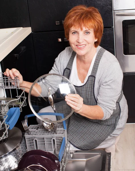 Mulher dobrando os pratos na máquina de lavar louça — Fotografia de Stock