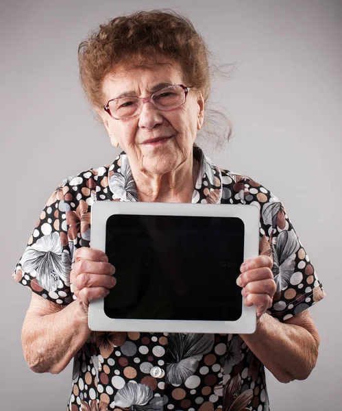 Gammal kvinna som håller en tablett i händerna på — Stockfoto