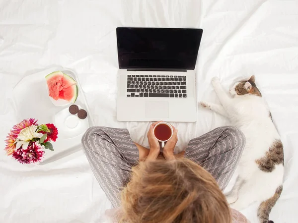 Jonge vrouw met laptop in het bed — Stockfoto