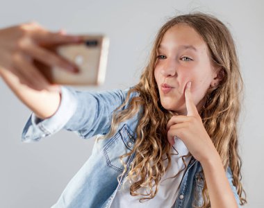 Gülümseyen genç beyaz arka plan sevimli kız üzerinde akıllı telefonda selfie fotoğraf yapma