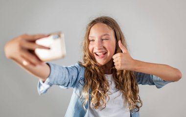 Gülümseyen genç beyaz arka plan sevimli kız üzerinde akıllı telefonda selfie fotoğraf yapma