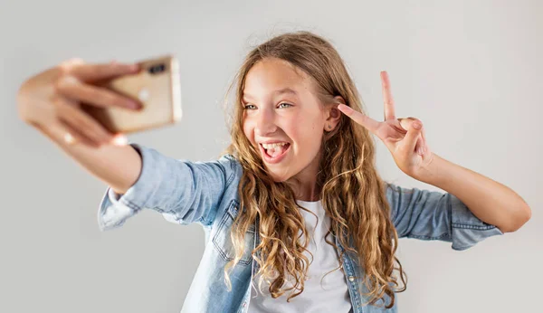 Sorrindo adolescente fazendo selfie foto no smartphone sobre fundo branco bonito menina — Fotografia de Stock