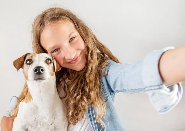 Sorrindo adolescente com cão fazendo foto selfie no smartphone sobre fundo branco bonito menina — Fotografia de Stock