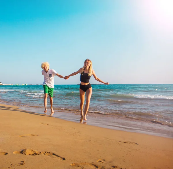 Счастливая молодая пара веселится на пляже в солнечный день — стоковое фото
