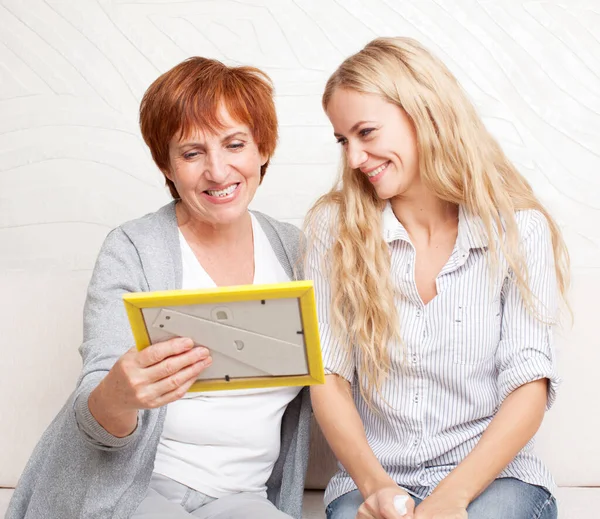 Mor med dotter tittar på fotoram — Stockfoto