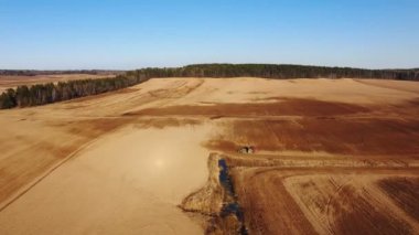 4k. Tarım sürecinin havadan görünümü: traktör pulluklar ve tohumlama yapar, alanda tarım bitkileri Ekim.