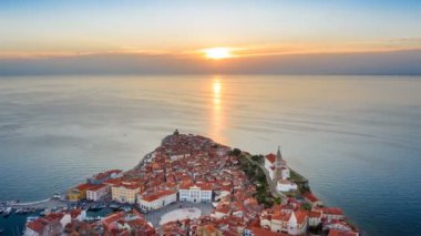 4k. Eski şehir Piran üzerinde gün batımı, eski evler, Tartini Meydanı, St George's Parish Kilisesi ve marina ile havadan panoramik görünümü. Time Lapse video.