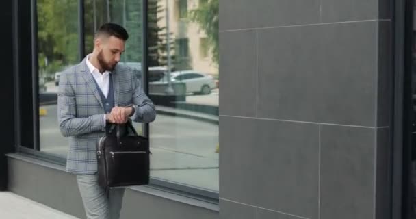 Молодой привлекательный студент-бизнесмен в костюме приходит с портфелем на вокзал, в аэропорт или бизнес-центр — стоковое видео