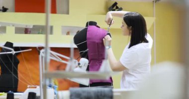 Genç kadın moda tasarımcısı Studio içinde çalışır. Giyim Tasarımcısı ölçümleri mankenler ile çalışma