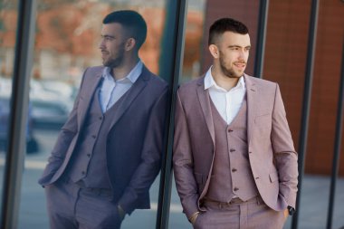 Akıllıca giyinen işadamı, Modern iş adamı. Arka planda bina ile tam takım açık havada duran kendine güvenen genç adam