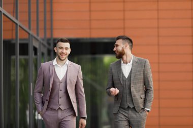 İki genç işadamları yürüyüş gülümseyen ve şehirde konuşuyor