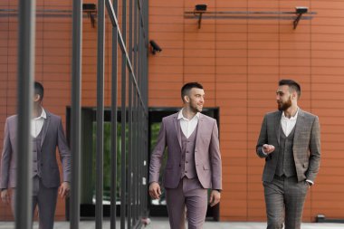 İki genç işadamları yürüyüş gülümseyen ve şehirde konuşuyor