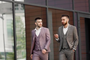 İki genç işadamları yürüyüş gülümseyen ve şehirde konuşuyor