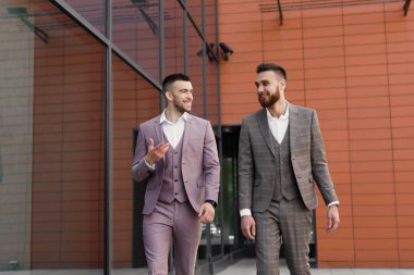 İki genç işadamları yürüyüş gülümseyen ve şehirde konuşuyor
