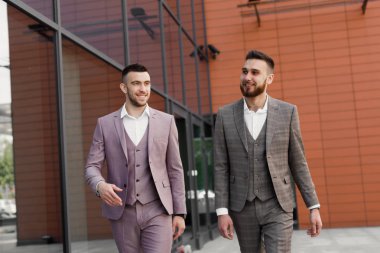 İki genç işadamları yürüyüş gülümseyen ve şehirde konuşuyor