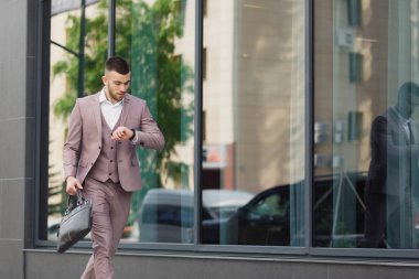 Bir şehirde sokak duvar bir arka plan üzerinde çalışan bir çanta ile genç işadamı