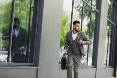 Bir şehirde sokak duvar bir arka plan üzerinde çalışan bir çanta ile genç işadamı