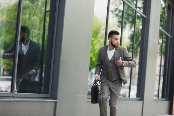 Bir şehirde sokak duvar bir arka plan üzerinde çalışan bir çanta ile genç işadamı
