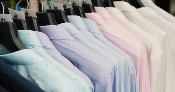 Συλλογή από νέα όμορφα ρούχα που κρέμονται στις κρεμάστρες σε ένα κατάστημα — Αρχείο Βίντεο
