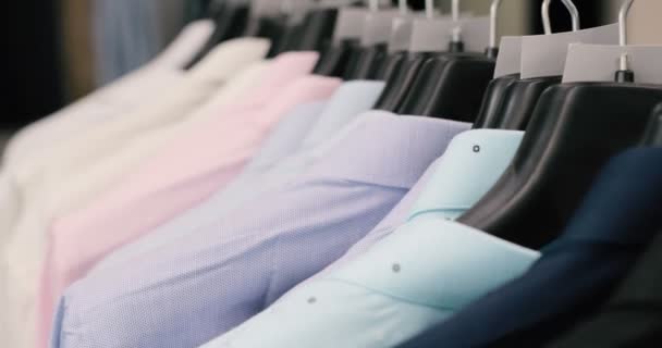 Коллекция новой красивой одежды висит на вешалках в магазине — стоковое видео