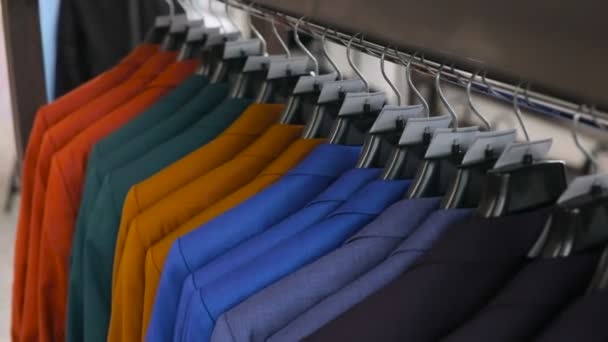 Row of men suit jackets on hangers. Collection of new beautiful clothes hanging on hangers in a shop. — Stock Video