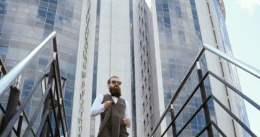 Bina ve etrafa büyük ofisinin dışında yürüyüş mutlu çekici beyaz iş adamı. Memnun ve mutlu görünen adam.