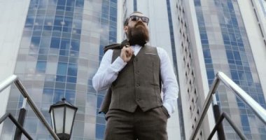 Bina ve etrafa büyük ofisinin dışında yürüyüş mutlu çekici beyaz iş adamı. Memnun ve mutlu görünen adam.