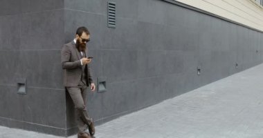 Etrafa ve modern binadan kalırken onun smartphone kullanarak çekici sakallı işadamı,