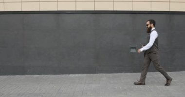 Bina ve etrafa büyük ofisinin dışında yürüyüş mutlu çekici beyaz iş adamı. Memnun ve mutlu görünen adam.