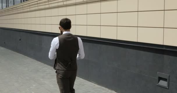 Boldog vonzó kaukázusi üzletember gyaloglás kívül közelében nagy office building, és körülnézett. Keresi a elégedett és boldog ember. — Stock videók